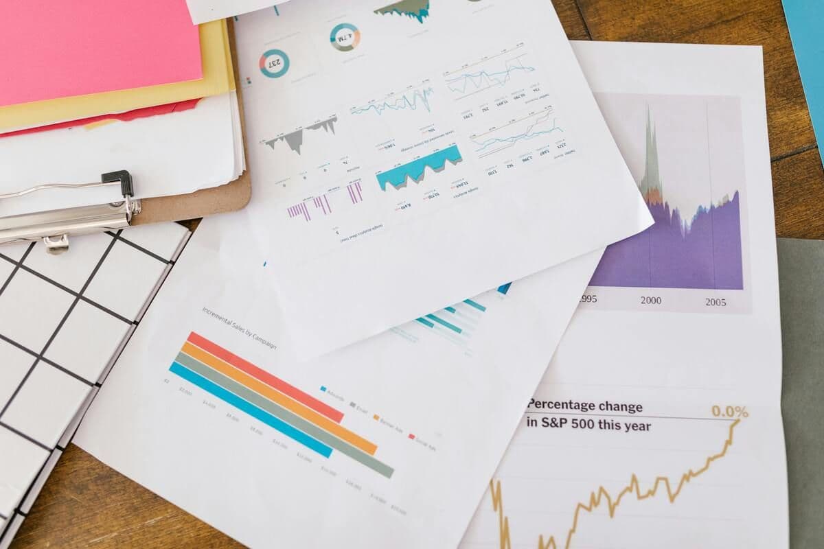 Financial charts and reports scattered on a wooden desk.
